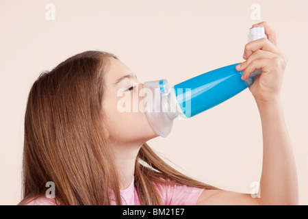 Fille à l'aide d'un inhalateur d'asthme relié avec l'entretoise Banque D'Images