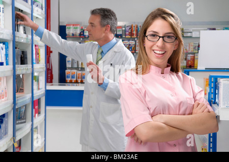 Female pharmacist smiling avec un homme pharmacien dans l'arrière-plan Banque D'Images