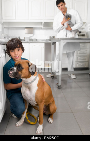 Garçon de caresser un chien avec un vétérinaire dans l'arrière-plan Banque D'Images