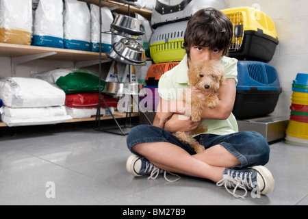 Garçon portant un chiot dans un supermarché Banque D'Images