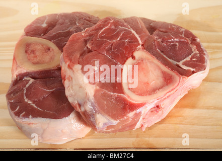 Deux pièces d'ossobuco (avec os steaks d'agneau) sur une planche à découper en bois Banque D'Images