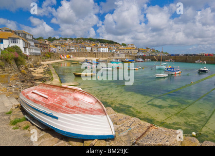 Tout petit bateau sur le quai et les petits bateaux dans le port clos à Mousehole, Cornwall, UK Banque D'Images