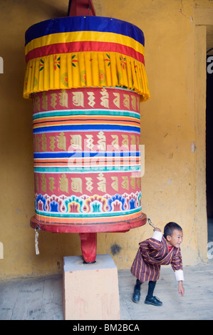 Jeune garçon tirant un moulin à prières, Jakar Dzong, Château de l'oiseau blanc, Jakar, Bumthang, Vallée Chokor, Bhoutan Banque D'Images