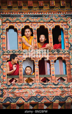 Les jeunes moines à une fenêtre, Chimi Lhakhang datant de 1499, le Temple du Lama Drukpa Kunley fou divin, Punakha, Bhoutan Banque D'Images