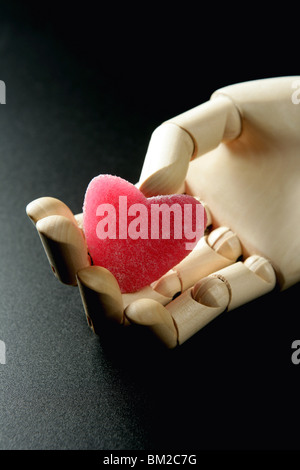 Mannequin de Bois tenant une gelée rouge en forme de coeur de bonbons Banque D'Images