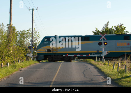 Un train de Via Rail se déplace dans un passage à niveau. Banque D'Images