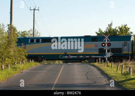 Un train de Via Rail se déplace dans un passage à niveau. Banque D'Images