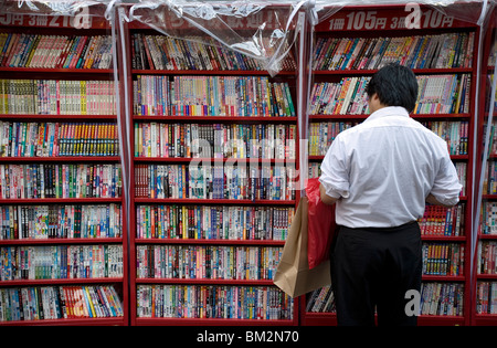 L'homme parcourt les mangas japonais comic books dans un magasin situé à Osaka, Japon Banque D'Images