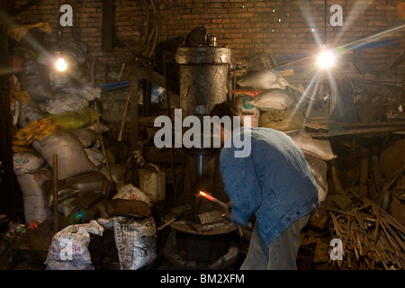 Un forgeron travailler sur une forge dans son atelier dans le Sichuan en Chine. Banque D'Images