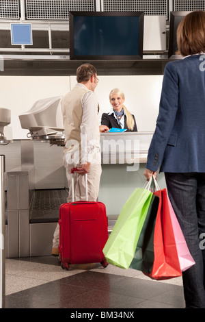 Un couple checking dans with shopping bags Banque D'Images