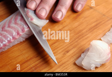 Man slicing la brème de mer Banque D'Images