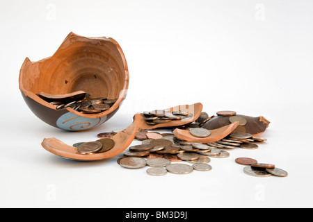 Broken terramundi pot d'épargne avec de l'argent s'échappe au-dessus de la table sur un fond blanc. Banque D'Images