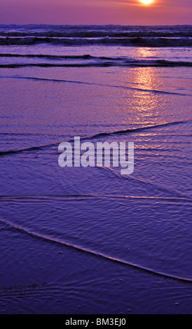 Cette superbe coucher du soleil est prise à l'océan avec des modèles intéressants des vagues arrivant sur la rive. Banque D'Images