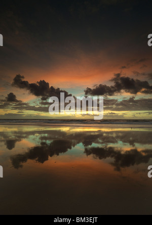 Les couleurs du crépuscule les nuages, car ils reflètent sur une plage à marée basse, la plage de Corrimal, NSW Australie Banque D'Images