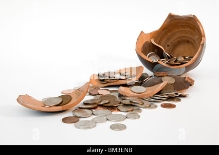 Broken terramundi pot d'épargne avec de l'argent s'échappe au-dessus de la table sur un fond blanc. Banque D'Images