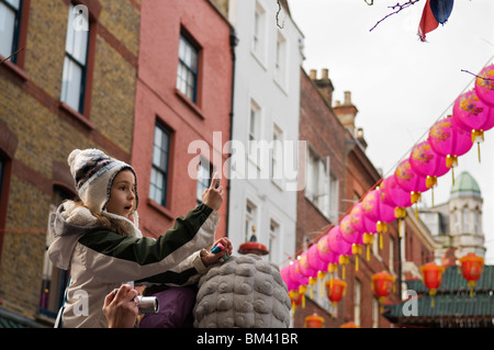 Littile fille de prendre une photo par Pierre Lion stature dans China Town, le festival du Nouvel An chinois 2010 London England UK Banque D'Images