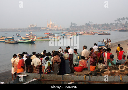 Les vendeurs et les acheteurs de poisson frais Contrôle de prendre du poisson dans l'arrière du terrain de bateaux de pêche et la mosquée,vizhinjam beach,Kerala, Inde Banque D'Images