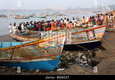 Les vendeurs et les acheteurs de poisson frais Contrôle de prendre du poisson dans l'arrière du terrain de bateaux de pêche et la mosquée,vizhinjam beach,Kerala, Inde Banque D'Images