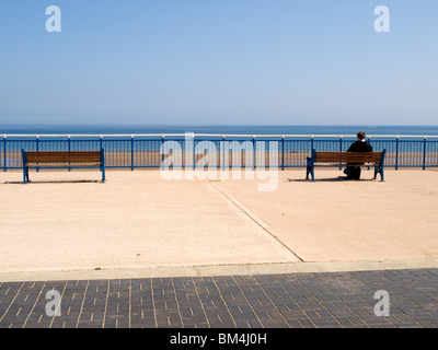 Printemps à la mer un homme est assis sur un siège et lit un livre par la mer Banque D'Images