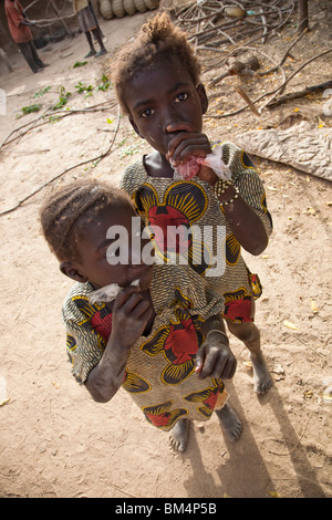 Deux jeunes filles dans le village de potiers de Kalabougou près de Ségou, Mali boissons glacées de sip blags en plastique. Banque D'Images