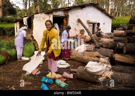 Une femme sourit et plie ses bagages après avoir terminé une journée de travail plateau picking sur un domaine dans le Nilgiri Hills dans le sud de l'Inde. Banque D'Images