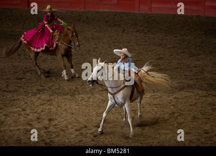 Un jeune charro, droite, et une fille, amazona gauche, montent leurs chevaux à une exposition dans la ville de Mexico, 8 juin 2008. Banque D'Images