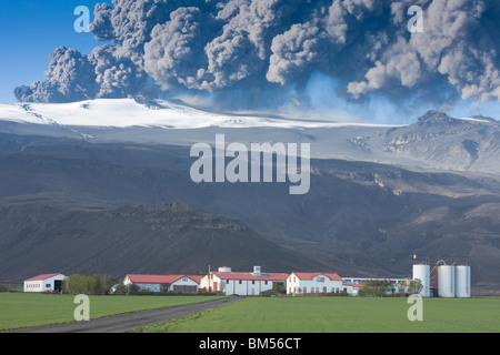 L'éruption du volcan Eyjafjallajokull en Islande crachant cendres dans l'air avec une ferme au-dessous de la montagne Banque D'Images