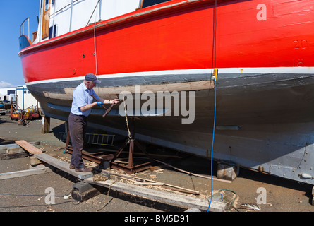 Navire Master Builder, John Gaff, la réparation de la coque d'un bateau de pêche en utilisant la méthode traditionnelle de l'étoupe d'emballage au sujet des lacunes Banque D'Images