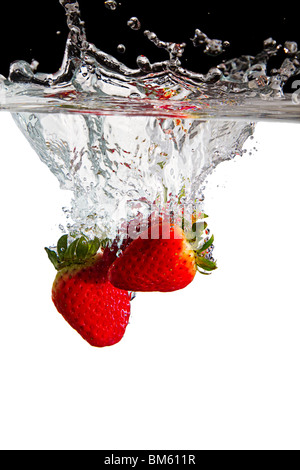 Quelques fraises jeté dans l'eau avec fond noir et blanc Banque D'Images