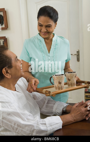 Femme portant un plateau pour un homme Banque D'Images