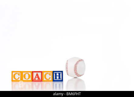 Enfants colorés blocks spelling coach avec une balle de baseball à l'arrière-plan Banque D'Images