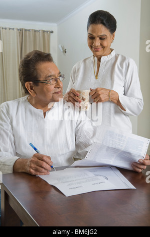 L'homme faire le tri des factures avec une femme à boire le thé à côté de lui Banque D'Images