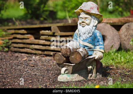 Nain de jardin avec brouette pleine de bois de chauffage Banque D'Images