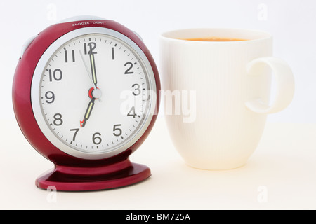 Tasse de thé rouge par un réveil à 7 h du matin à seulement quelques secondes avant que l'alarme sonne au moment de se lever. Angleterre Royaume-uni Grande-Bretagne Banque D'Images