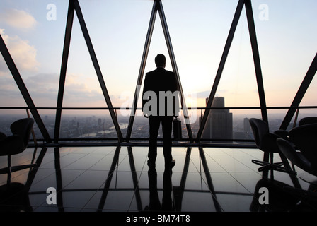 Un homme d'affaires stand avec son porte-documents en haut de le Gherkin gratte-ciel dans la ville de Londres, au Royaume-Uni. Banque D'Images