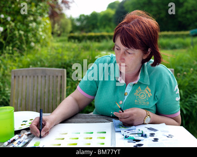 Peinture femme dans un jardin anglais au printemps. Banque D'Images