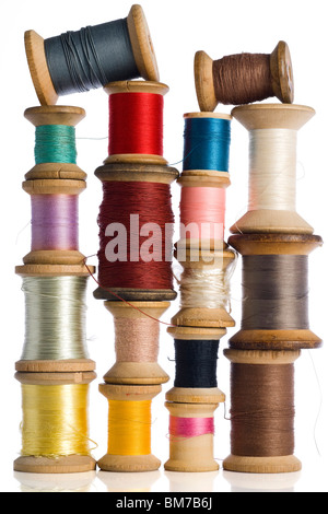 Une collection de bobines de fil en bois coloré sur fond blanc Banque D'Images