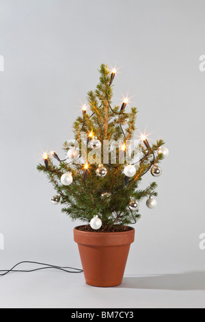 Un petit sapin décoré de boules et lumières Banque D'Images