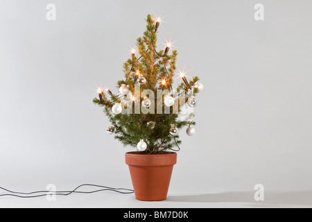 Un petit sapin décoré de boules et lumières Banque D'Images