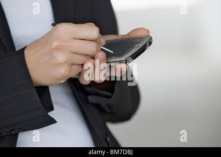 Une femme à l'aide d'un agenda électronique et numérisés stylo, détail des mains Banque D'Images