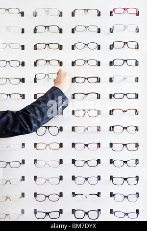 Une main humaine le choix d'une paire de lunettes dans un magasin de lunettes Banque D'Images