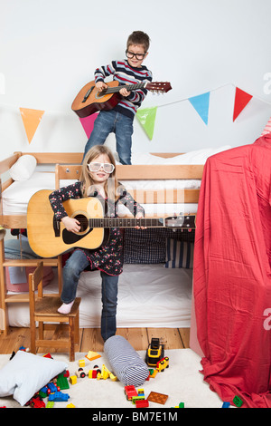 Deux enfants jouant avec des guitares dans une salle de jeux pour enfants Banque D'Images