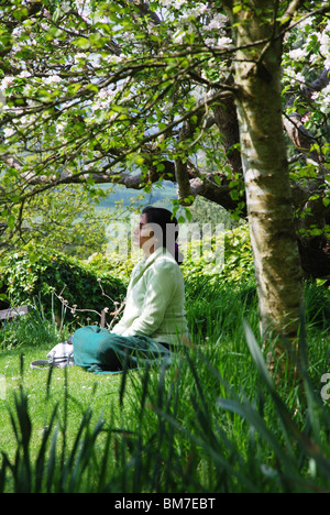 Femme méditant dans les jardins de Chalice Well Somerset Glastonbury Angleterre Royaume-Uni Banque D'Images