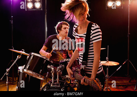 Un homme à jouer de la batterie et d'une femme qui joue de la guitare dans un groupe de rock sur scène Banque D'Images