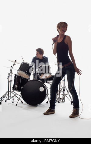 Une chanteuse et un homme à la batterie d'effectuer, studio shot, fond blanc, éclairage arrière Banque D'Images