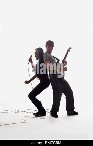 Une chanteuse et un homme jouant de la guitare électrique, studio shot, fond blanc, éclairage arrière Banque D'Images