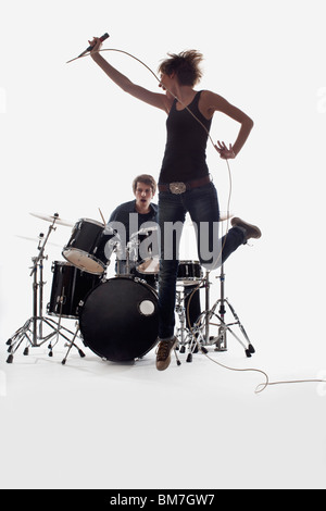 Une chanteuse d'un saut et qu'un homme sur la batterie de la scène, Studio shot, fond blanc, éclairage arrière Banque D'Images