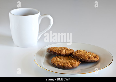 Tasse de café noir blanc et chocolat cookies trois friable sur une plaque blanche Banque D'Images