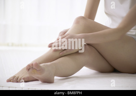 Jeune femme à masser les jambes dans la salle de bains, Close up Banque D'Images