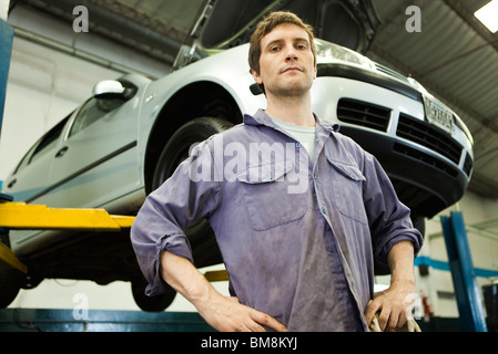 Mécanicien dans atelier de réparation automobile, at en arrière-plan Banque D'Images